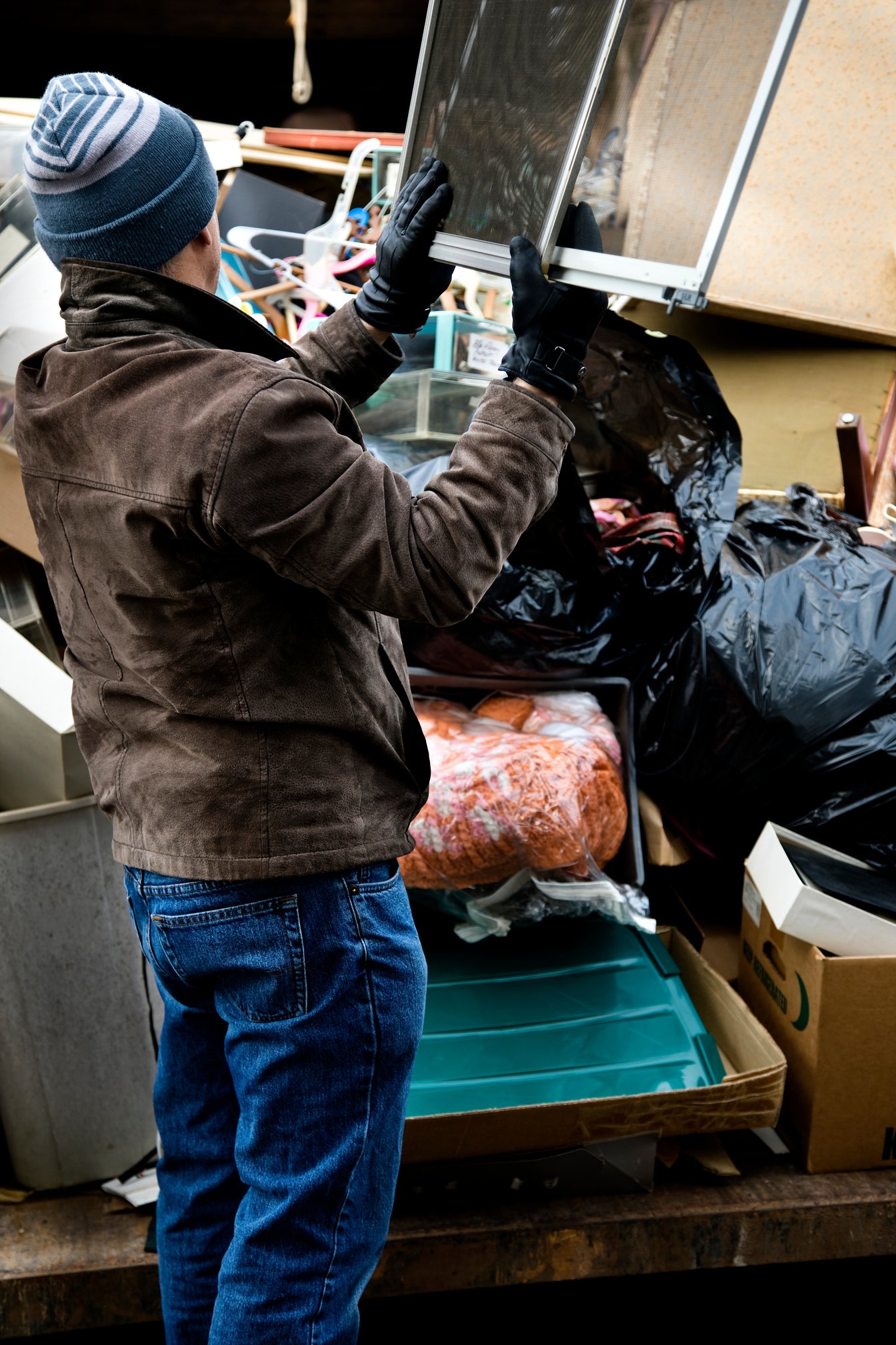 Workman tossing junk in dumpster